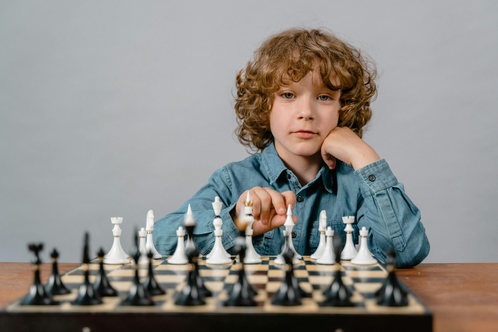 A thoughtful child playing chess, focusing on strategic moves with a serious expression. Life skills & Holistic learning