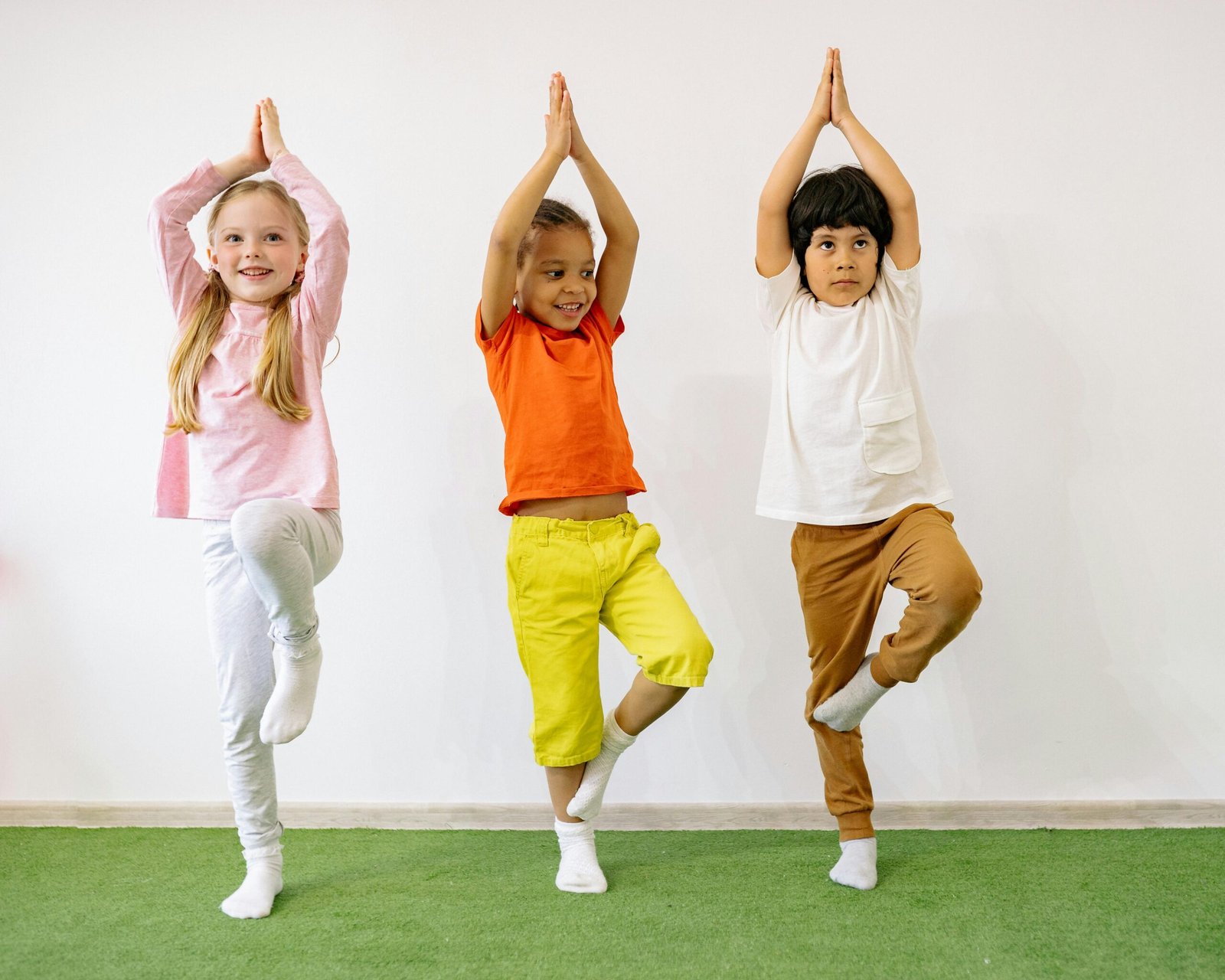 Three diverse children practicing yoga indoors, showcasing joy and balance. Life skills & Holistic learning